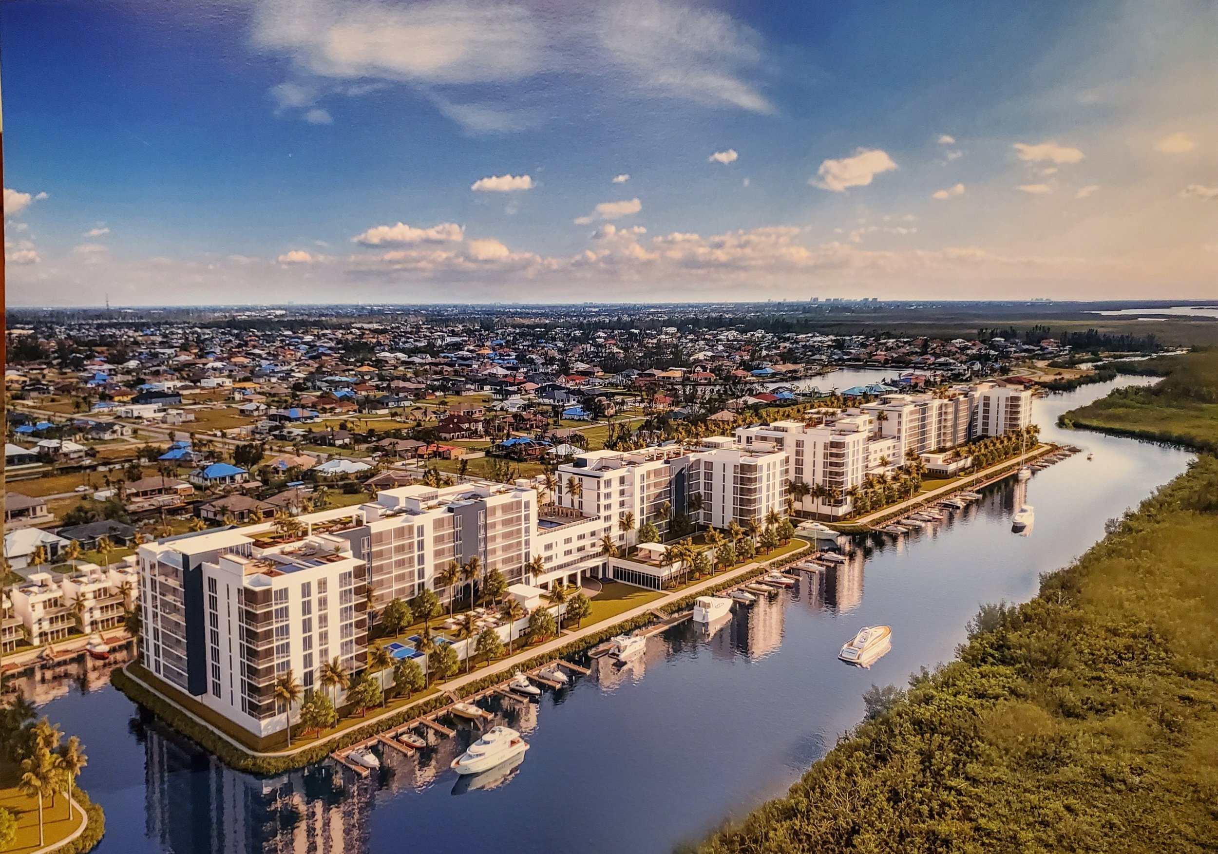 Seven Islands canal-front master-plan view. The aerial concept looks along the canal frontage and shows a continuous line of mid-rise buildings, marina slips, waterfront residences and the adjoining mangrove preserve.